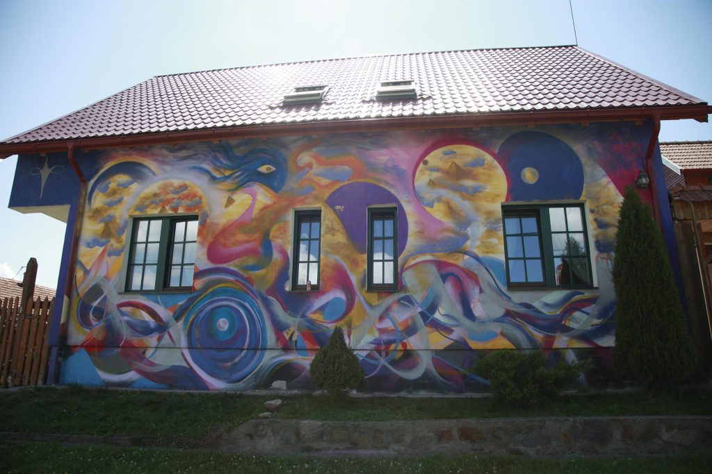 House facade covered in a colorful mural by Daniel Gaciu