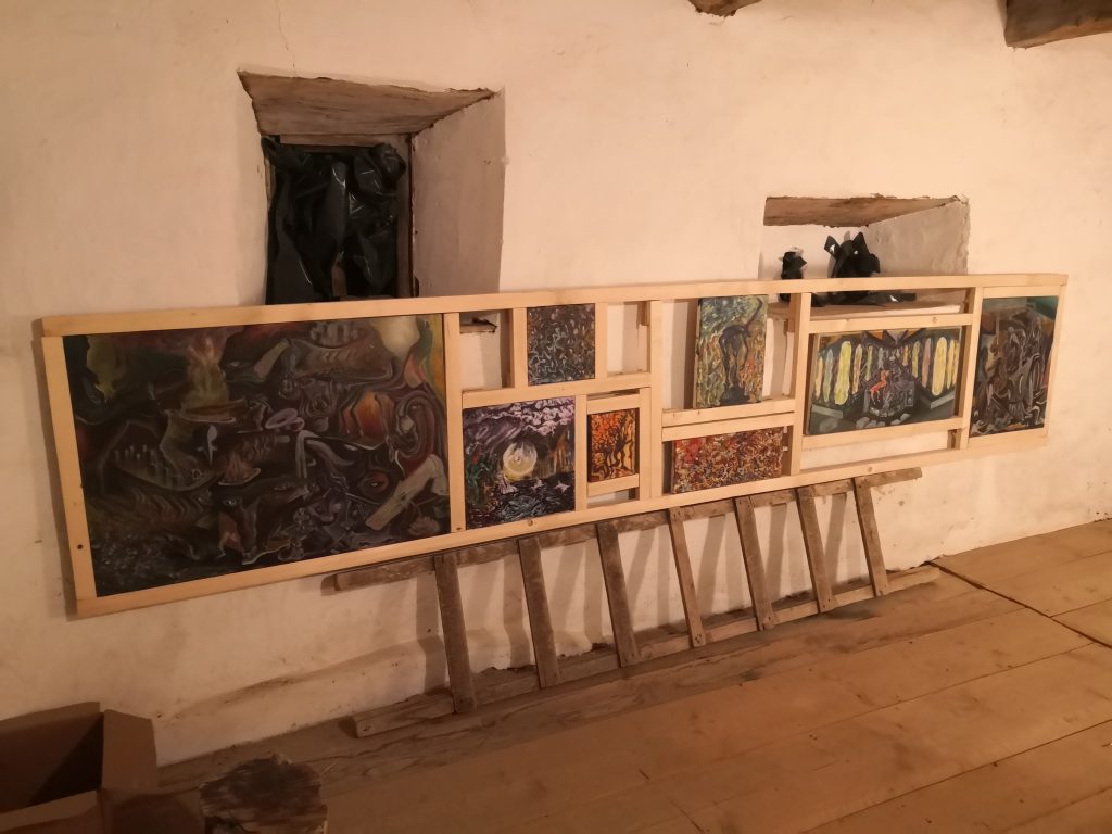 Picturi de Daniel Gaciu expuse pe stative într-o încăpere rustică, Trans Fort, Apold