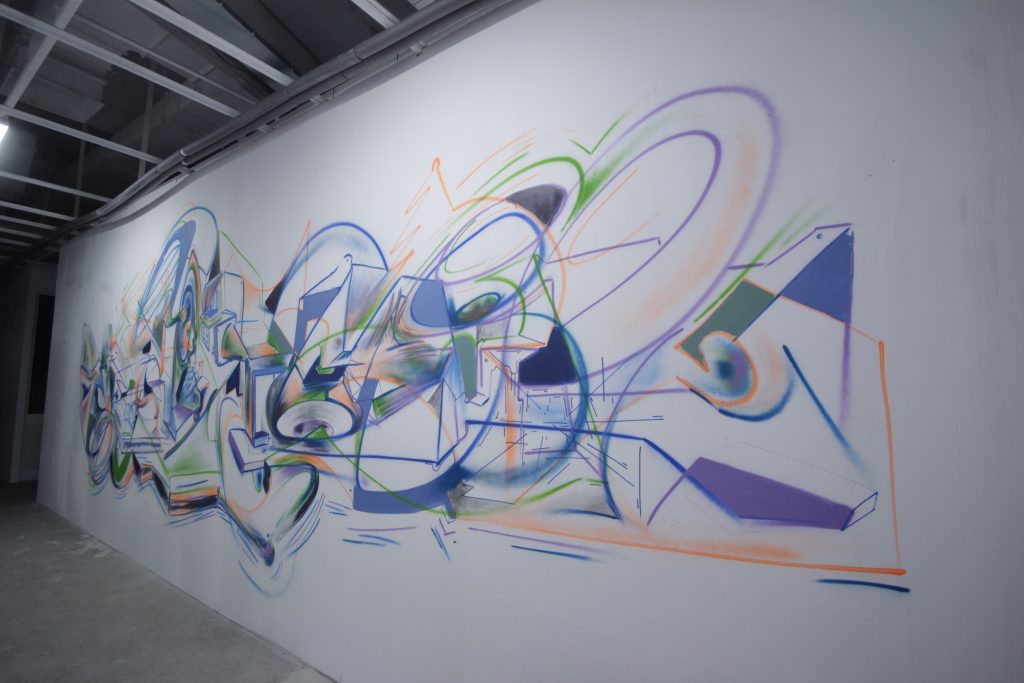 Abstract mural by Daniel Gaciu on a long white wall