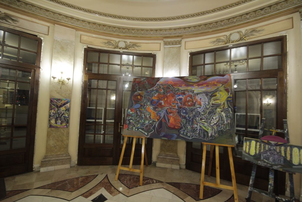 Pictură de Daniel Gaciu pe un șevalet în sala decorată a Cercului Militar Național, București