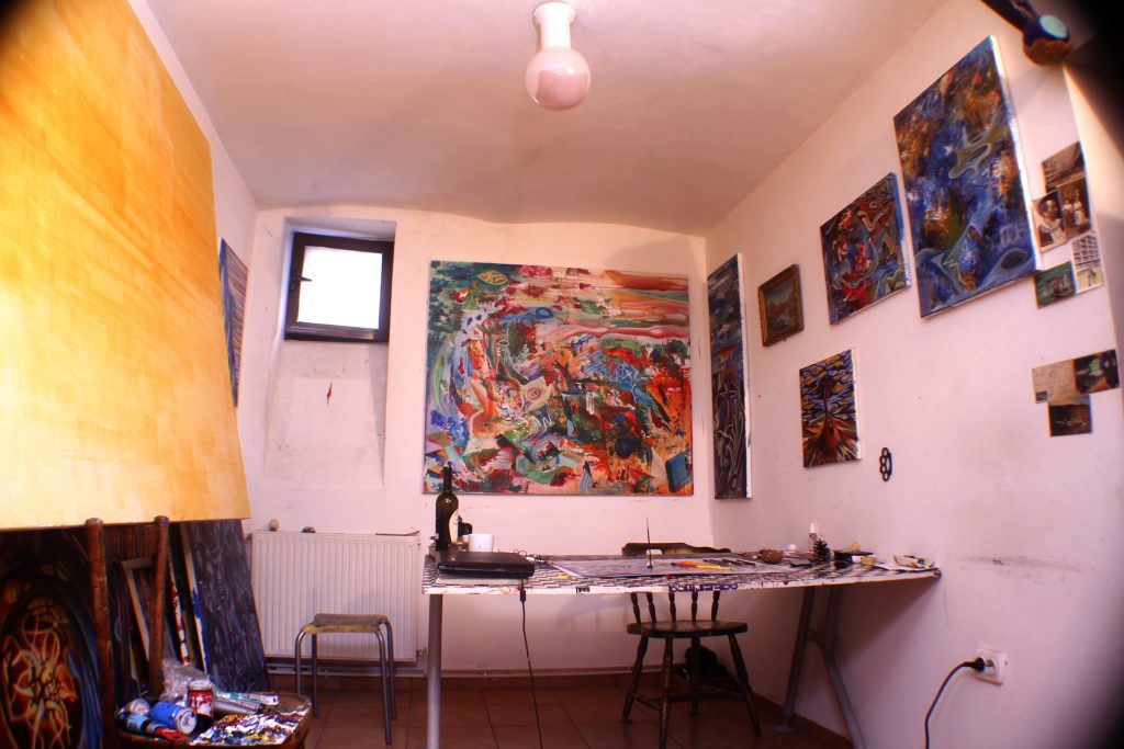 Room with paintings on the walls and a work table in the atelier